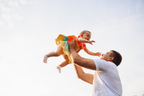 happy-father-holds-charming-little-girl-up-summer-sky.