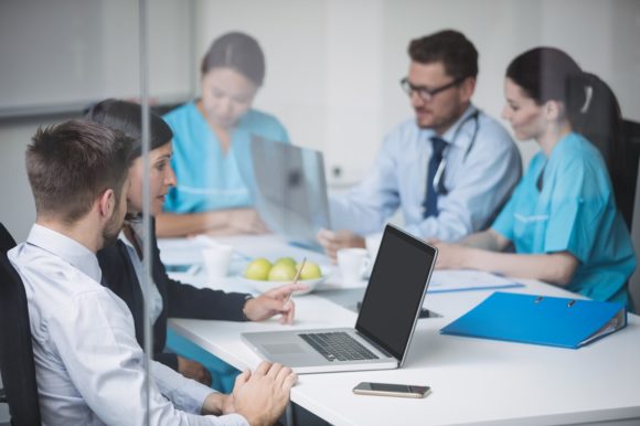 Doctors discussing over laptop in meeting at conference room
