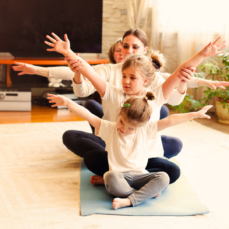 group of children on a yoga mat with their arms stretched out